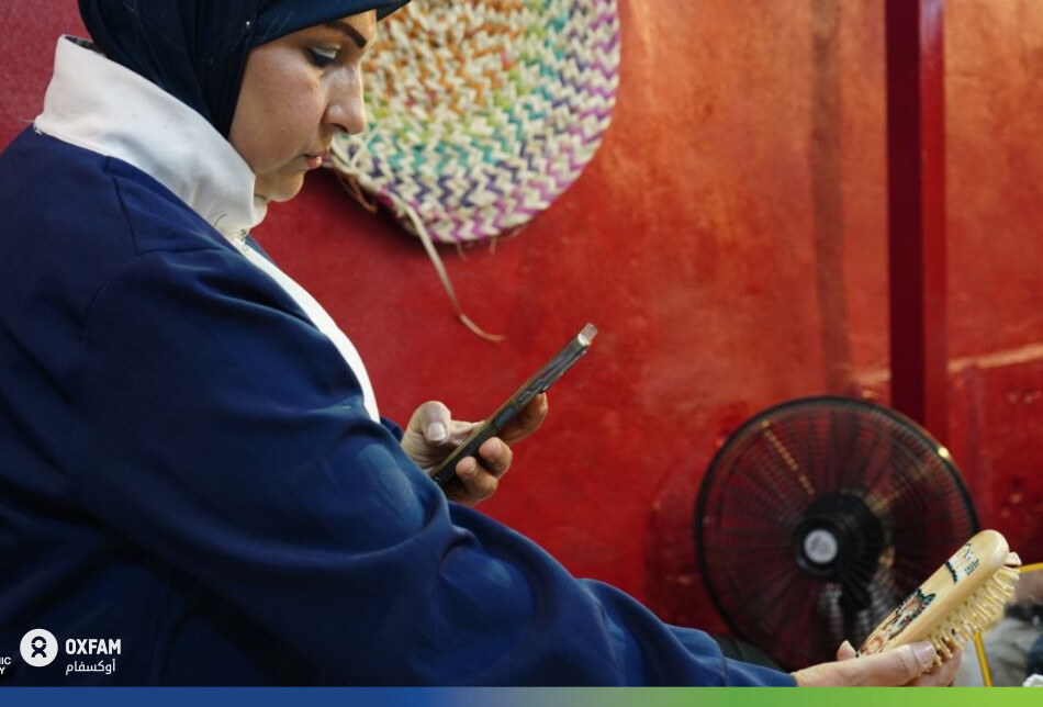 في لحظة تركيز شديد، تدمج آمال بين أصالة الخط اليدوي والتصاميم الحديثة مستعينة بهاتفها لتلبية أذواق زبائنها. تتنوع مهاراتها بين الرسم على الزجاج، والخط على الأخشاب والدفاتر، وصناعة المحافظ، وتنظيم كوشات الأفراح والمناسبات.
